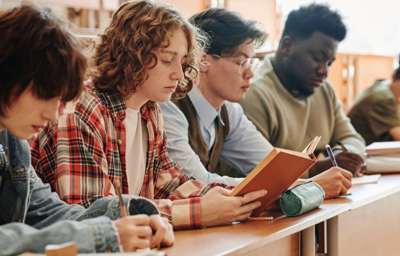 Estudiantes tomando apuntes uno al lado del otro en un aula